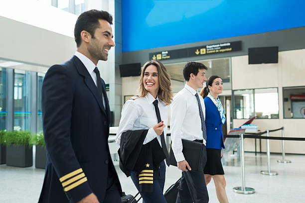 Plane crew walking in airport terminal near airline office.