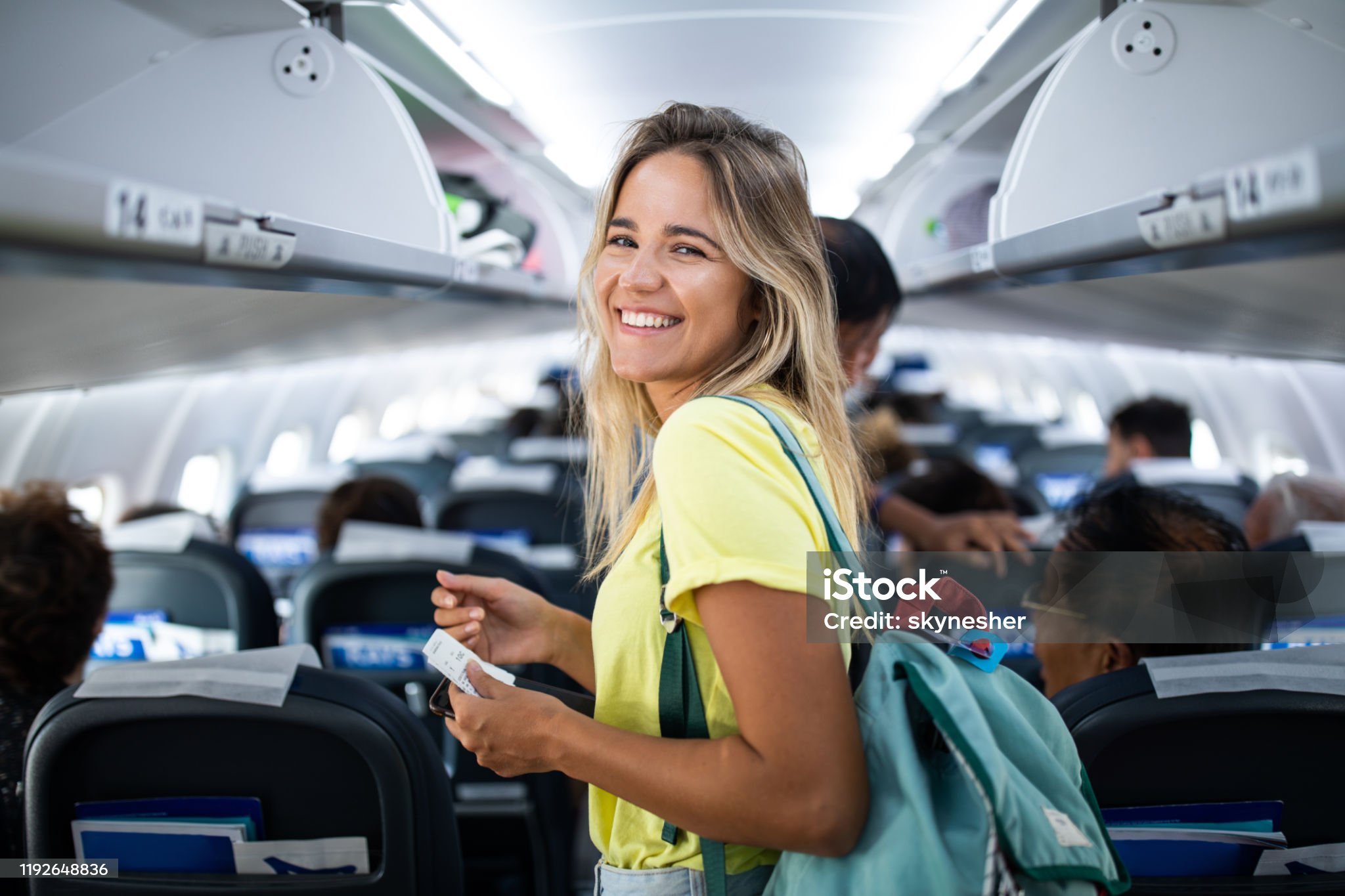 Happy woman boarding the airplane and looking at camera.